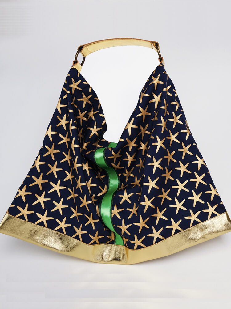 The Night Nut handbag combines genuine leather and Pharaonic-inspired cotton print. The golden stars print on the navy blue complement the gold leather,